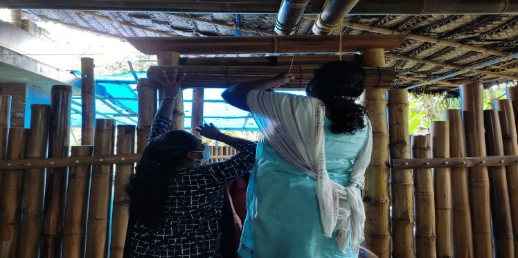 Ramya and Saritha unfolding a bamboo curtain